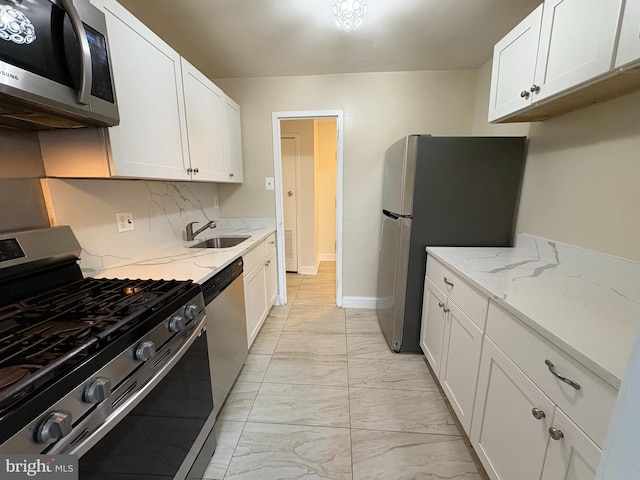 kitchen featuring stainless steel appliances, a sink, light marble finish flooring, white cabinets, and light stone countertops