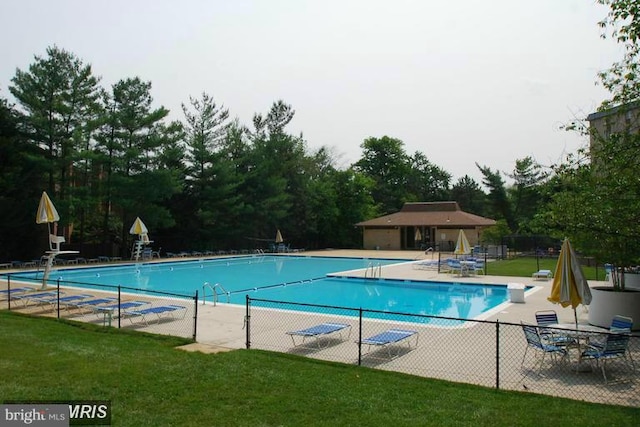 community pool with a patio area and view of scattered trees
