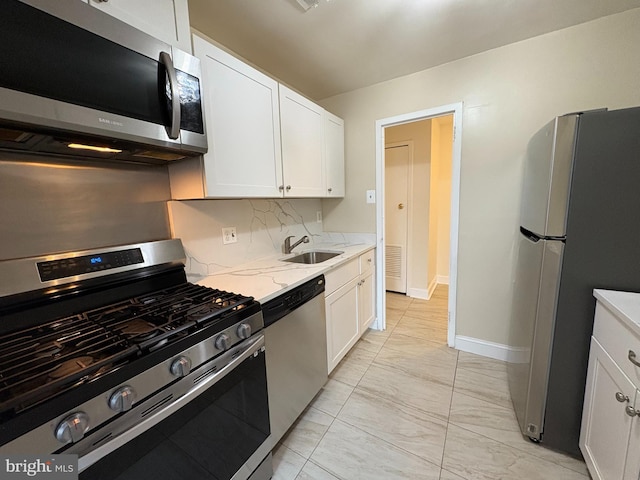 kitchen with stainless steel appliances, a sink, light marble finish flooring, and white cabinets