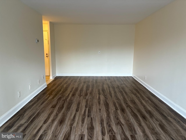 spare room featuring dark wood-style flooring and baseboards