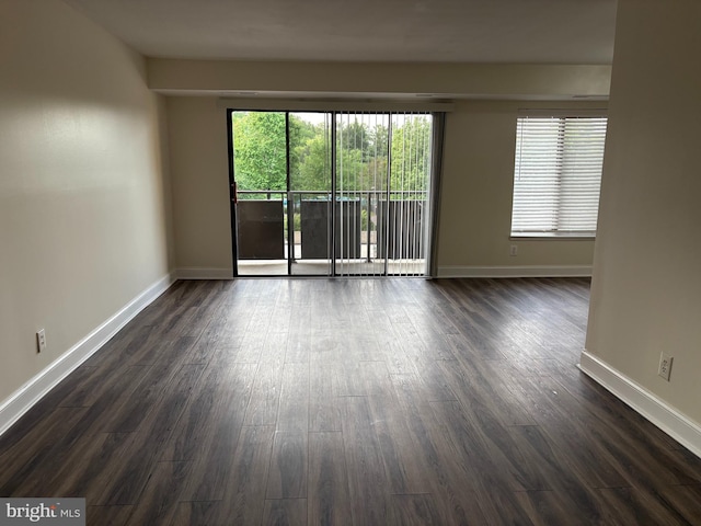 spare room featuring dark wood-style floors and baseboards