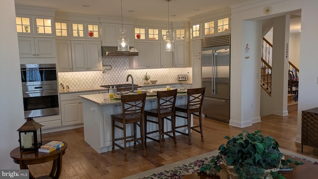 16 Magpie Ln, Princeton Junction, NJ 08550 - kitchen featuring appliances with stainless steel finishes, wood finished floors, a kitchen island with sink, white cabinetry, and crown molding