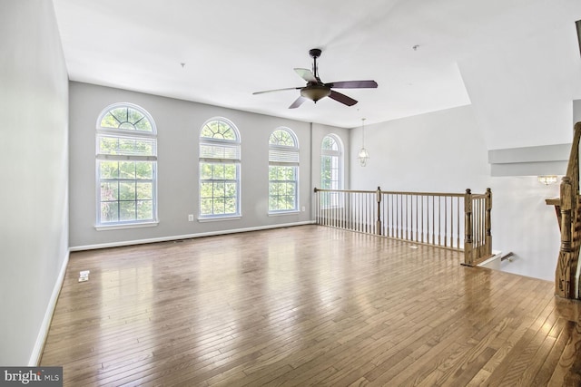unfurnished living room with a ceiling fan, hardwood / wood-style floors, and baseboards
