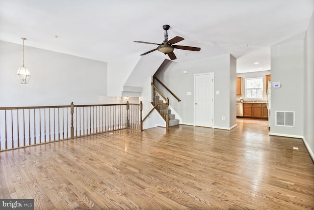 unfurnished living room with a ceiling fan, light wood-type flooring, and baseboards