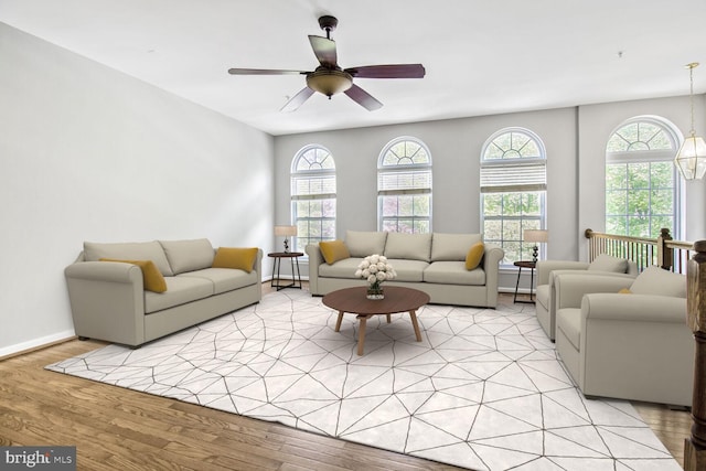 living room featuring light wood-style flooring, a ceiling fan, and baseboards