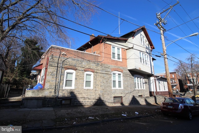 view of side of property featuring stone siding and a chimney