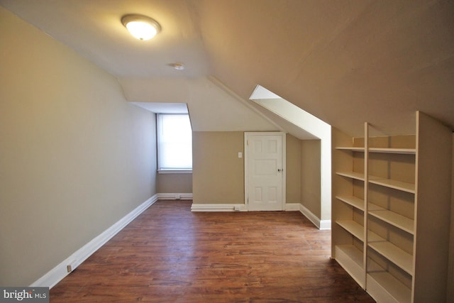 bonus room with dark wood-style floors, lofted ceiling, and baseboards