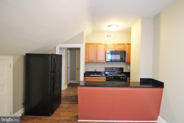 kitchen with black appliances, a peninsula, vaulted ceiling, dark countertops, and dark wood finished floors