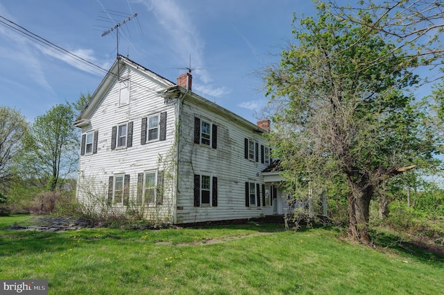 back of property featuring a chimney and a lawn