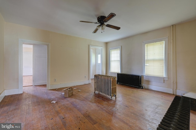 empty room with ceiling fan, wood-type flooring, radiator heating unit, and baseboards