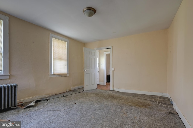 unfurnished room featuring radiator heating unit, carpet, and baseboards