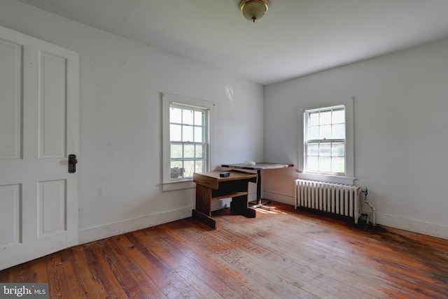 office space featuring radiator heating unit, plenty of natural light, hardwood / wood-style floors, and baseboards