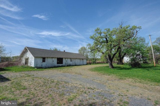 view of front of home with dirt driveway and a front lawn
