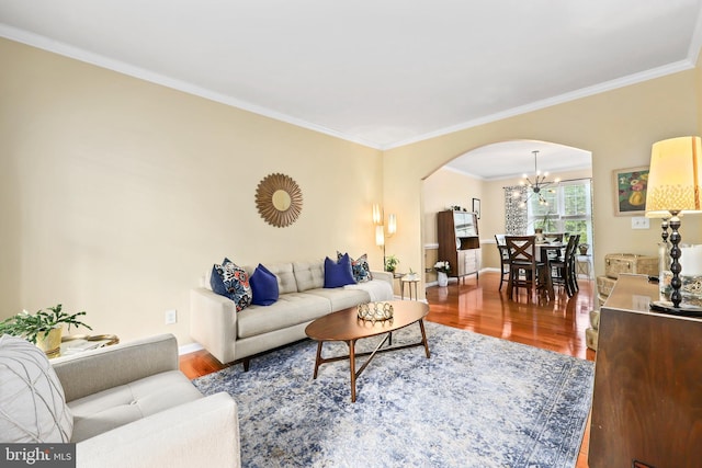 living room with arched walkways, a chandelier, wood finished floors, crown molding, and baseboards