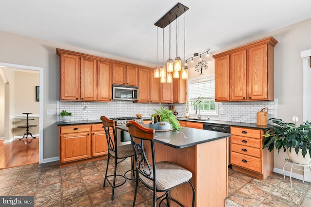 kitchen featuring stainless steel appliances, dark countertops, brown cabinetry, and a breakfast bar