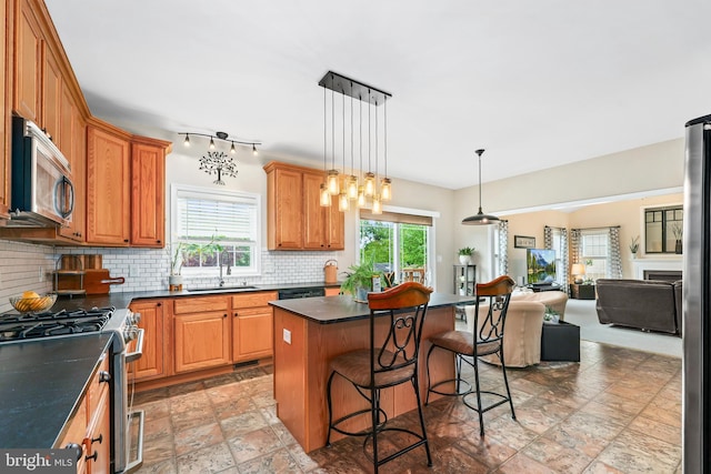 kitchen with stainless steel appliances, dark countertops, open floor plan, and a sink
