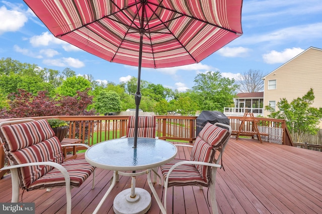 wooden deck featuring a sunroom and outdoor dining space