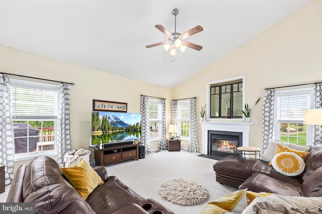 living room with a ceiling fan, a fireplace with flush hearth, carpet, plenty of natural light, and high vaulted ceiling
