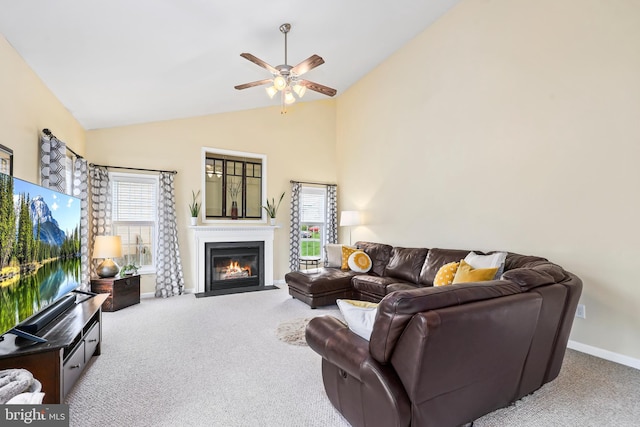 carpeted living room with plenty of natural light, ceiling fan, lofted ceiling, a fireplace with flush hearth, and baseboards