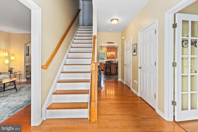 foyer featuring wood finished floors, stairway, arched walkways, and baseboards