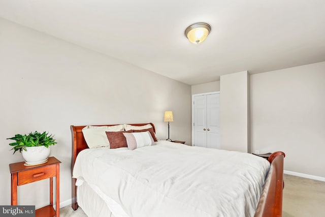 bedroom with light colored carpet, baseboards, and a closet