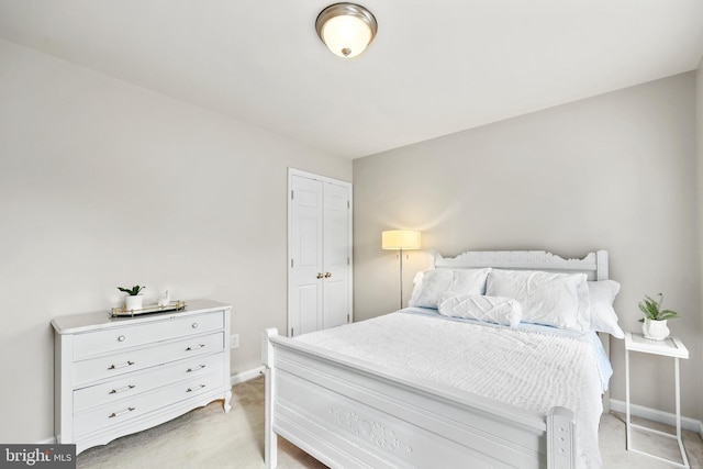 bedroom with light colored carpet, baseboards, and a closet