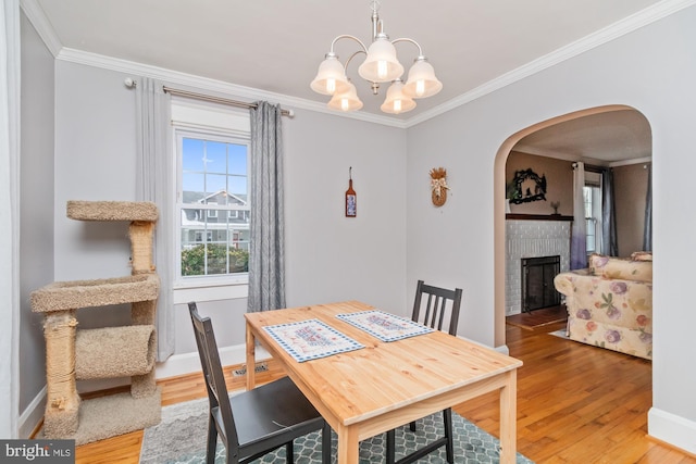 5100 Eugene Ave, Baltimore, MD 21206 - dining room featuring wood finished floors, a chandelier, arched walkways, a fireplace, and crown molding
