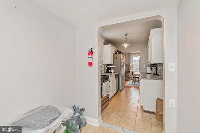 5100 Eugene Ave, Baltimore, MD 21206 - kitchen with appliances with stainless steel finishes, white cabinets, decorative backsplash, light tile patterned floors, and decorative light fixtures