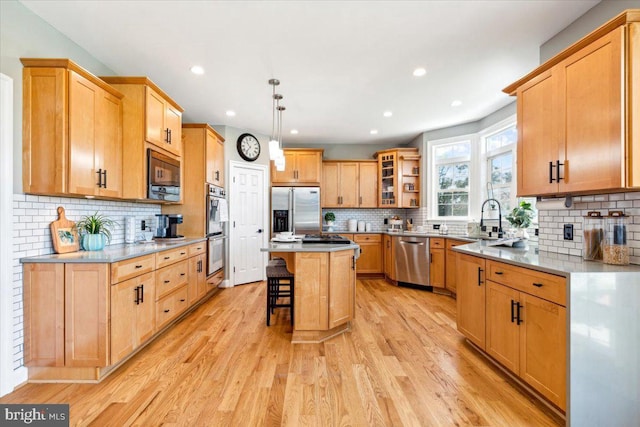 kitchen featuring appliances with stainless steel finishes, a breakfast bar area, tasteful backsplash, a sink, and a kitchen island