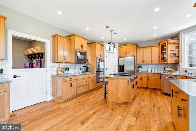 kitchen with stainless steel appliances, tasteful backsplash, light wood-style floors, a kitchen breakfast bar, and a kitchen island