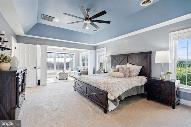 bedroom with light carpet, a tray ceiling, baseboards, and ceiling fan