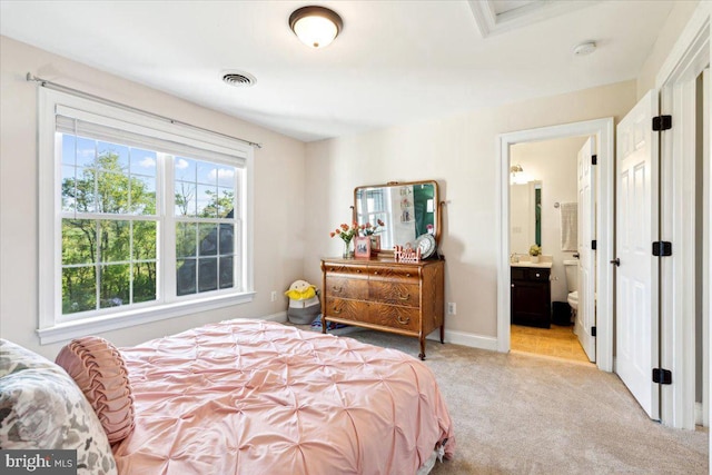 bedroom featuring light colored carpet, ensuite bath, and baseboards