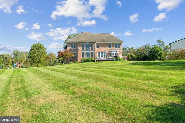 rear view of property featuring a yard and brick siding