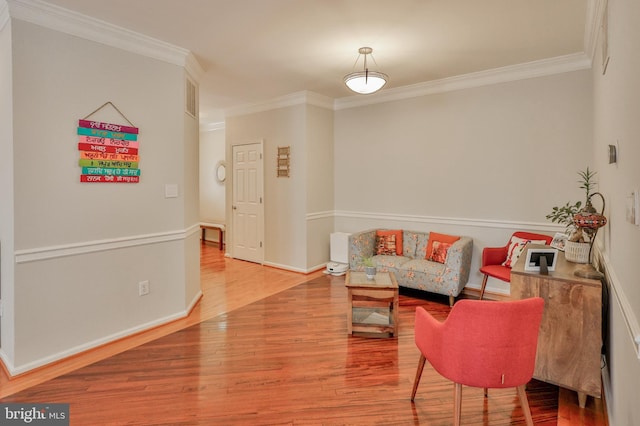 living area with crown molding, wood finished floors, and baseboards