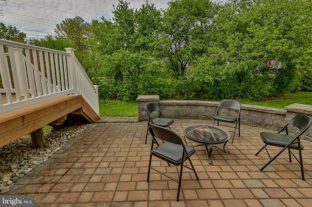 view of patio featuring an outdoor fire pit and view of wooded area