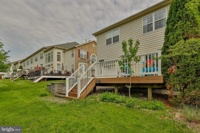back of house featuring stairs, a deck, and a lawn
