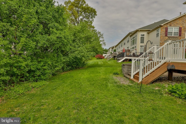 view of grassy yard with stairway and a deck