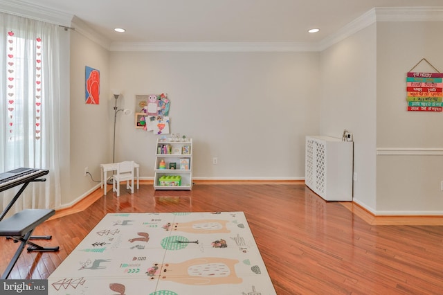 recreation room featuring crown molding, wood finished floors, baseboards, and recessed lighting
