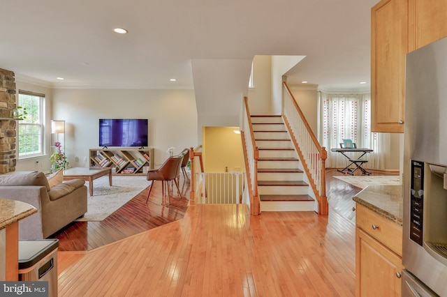 living area with crown molding, light wood-style flooring, recessed lighting, and stairs