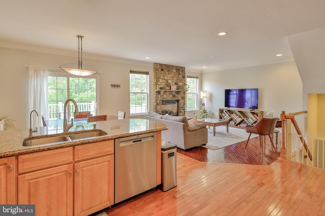 kitchen with dishwasher, a sink, light wood-type flooring, light stone countertops, and ornamental molding