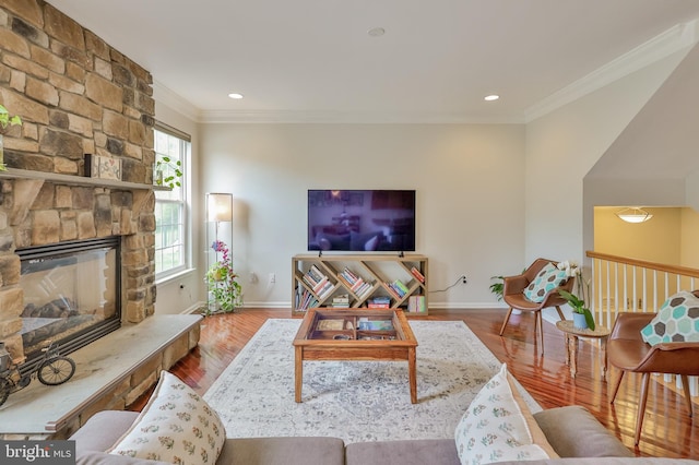 living room with crown molding, wood finished floors, baseboards, a fireplace, and recessed lighting
