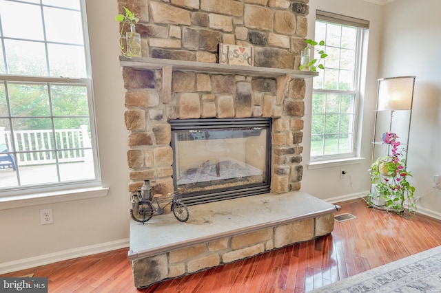 detailed view of baseboards, wood finished floors, and a stone fireplace