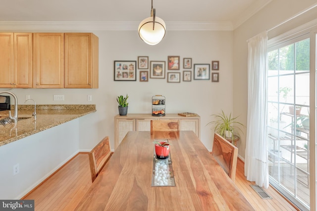dining area with light wood-style floors, crown molding, and baseboards