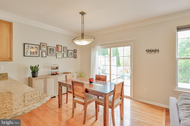 dining room with light wood finished floors, ornamental molding, and baseboards