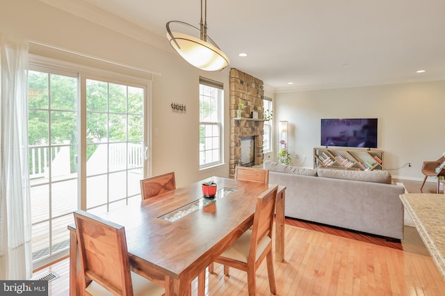dining area with a fireplace, ornamental molding, light wood finished floors, and recessed lighting