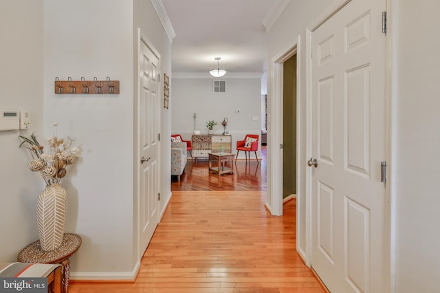 hallway with ornamental molding, light wood-style flooring, and baseboards