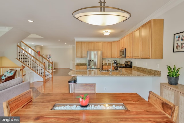 kitchen with appliances with stainless steel finishes, a sink, a peninsula, ornamental molding, and light stone counters