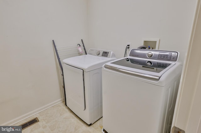 washroom with separate washer and dryer, light tile patterned floors, and baseboards