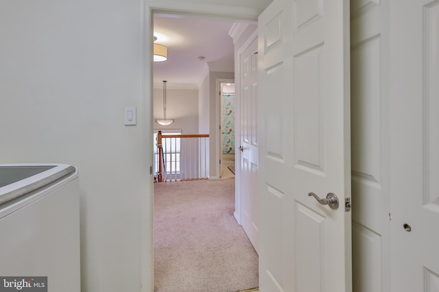 hall featuring ornamental molding, carpet, washer / dryer, and an upstairs landing
