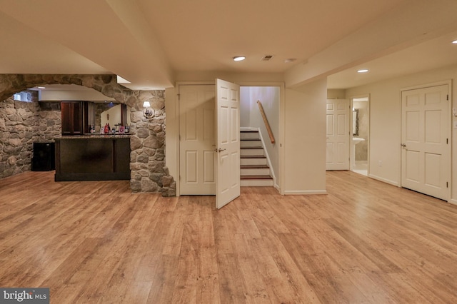 finished below grade area with stairway, light wood-style floors, recessed lighting, baseboards, and bar area